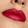 Lips wearing ColourPop Bichette Lippie Stix, showcasing a vivid crimson-red shade with a smooth satin finish and crisp edges, captured in a tight close-up against natural skin to highlight color payoff.