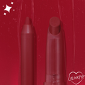 ColourPop Lippie Pencil in Bichette stands uncapped beside the matching Lippie Stix on a glossy deep red swatch background with sparkle accents and a heart-shaped ColourPop logo, showcasing its rich wine-red shade and precise tip.