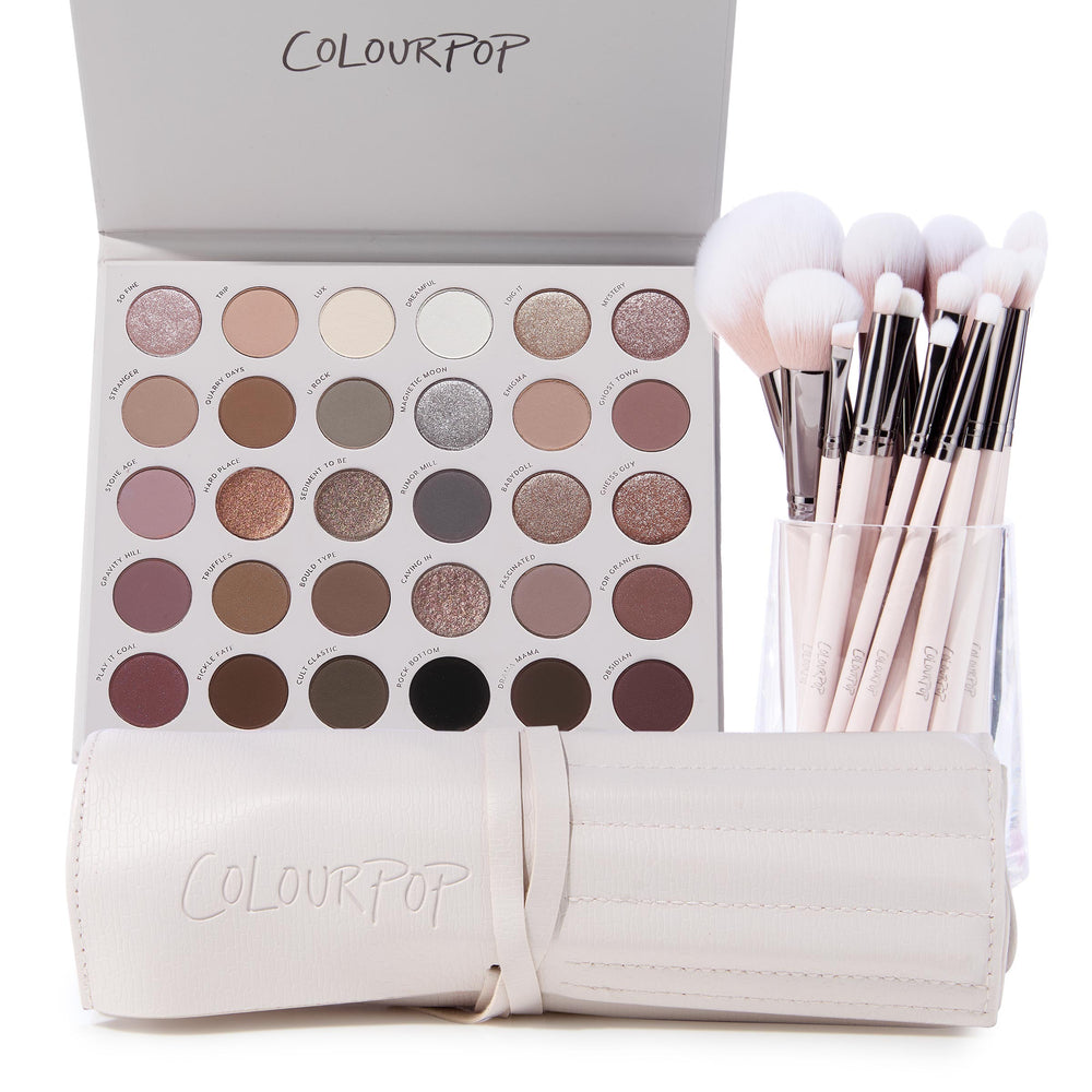 The Ultimate Stunner ColourPop Shadow Palette & Brush Set displaying an open 30‑pan neutral matte and shimmer eyeshadow palette beside pink‑handled makeup brushes in a clear cup and a cream brush roll, on a white background.