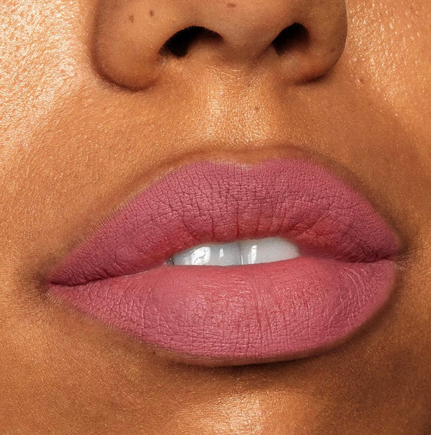 Close-up lips wearing Cami, a dusty rose ColourPop Lippie Stix, showing full, even coverage with a soft-matte finish; teeth slightly visible, studio lighting highlights smooth texture.
