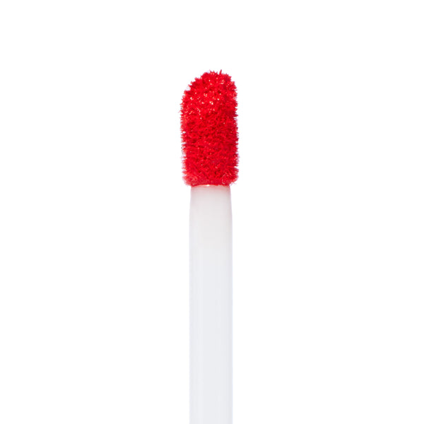 Doe-foot applicator coated with vibrant red pigment showcases Clock Out Ultra Matte Lip, a ColourPop Ultra Matte Lip, in a sharp macro close-up on a white background, highlighting the plush texture and precise tip for smooth application.