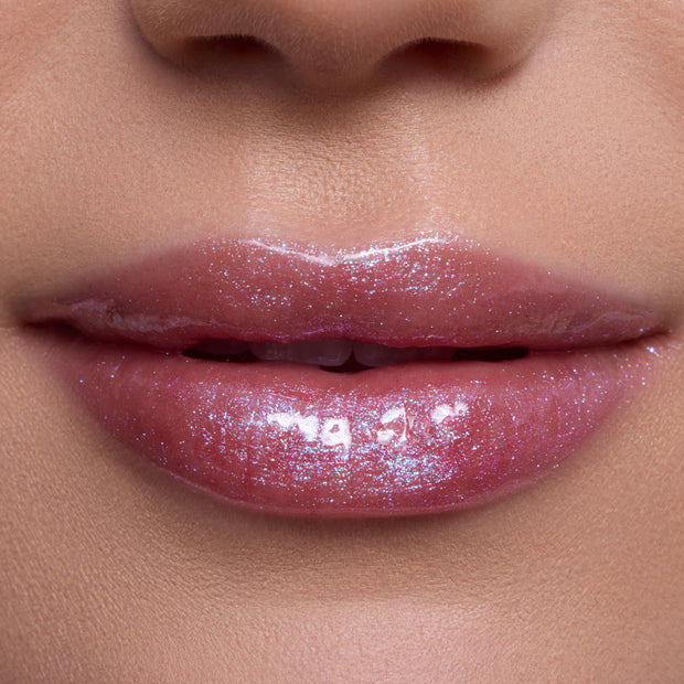 Close-up of lips wearing Courageous Rapunzel Ultra Glossy Lip, a shimmering pink Disney Princess lip gloss with high-shine, iridescent sparkle on smooth, hydrated lips against natural skin tone background.