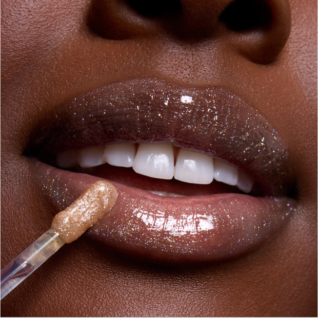 Close-up of glossy, glittering lips being coated with shimmering nude Princess Pout lip gloss from the Disney Princess full collection set, highlighting high-shine finish and sparkle detail for US beauty lovers.