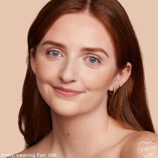 ColourPop Pretty Fresh Creamy Concealer in Fair 10 N brightening under eyes and evening skin tone on a smiling model; close-up portrait against a peach background shows light‑neutral coverage with a natural, satin finish.