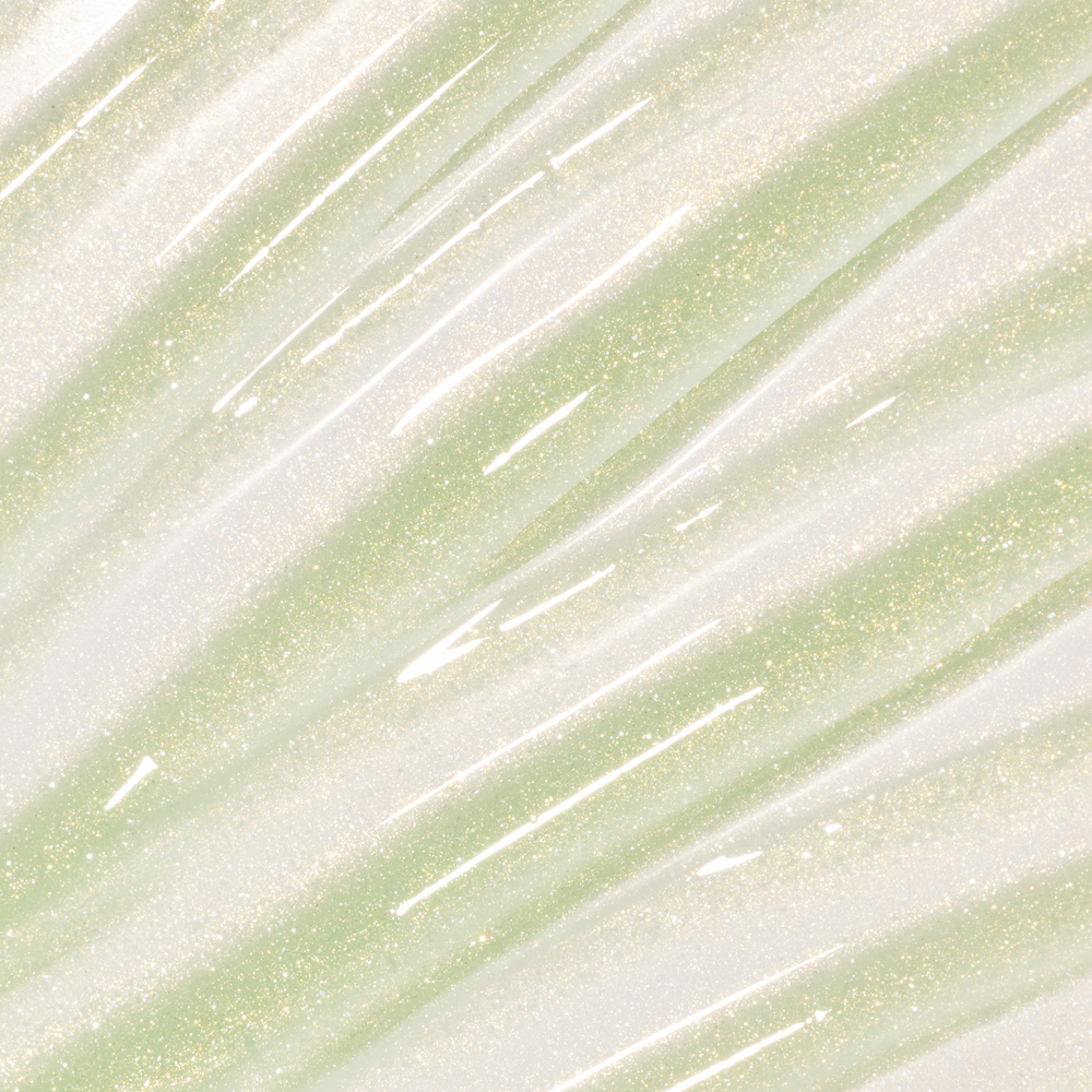 Colourpop Fresh Kiss Glossy Balm in Vanilla Matcha swatched as sheer gold and pale green lip gloss & lip oil with fine gold and silver sparkle streaks across the background, showcasing its shimmery, high-shine finish.