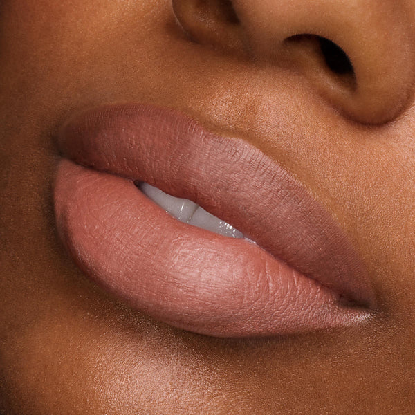 Full lips wearing ColourPop Power Pout Lipstick, Bella! Where the Hell Have You Been, Loca?, showcasing a creamy nude-rose shade with a soft-matte finish in a studio close-up, emphasizing smooth texture, precise edges, and full-coverage payoff.