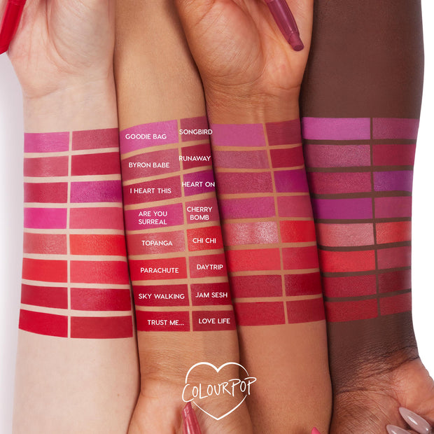 Byron Babe ColourPop Lippie Stix swatched on three arms, showcasing its rosy mauve shade among labeled swatches, with a Lippie Stix pen held near the wrists and a ColourPop heart logo on a white background.