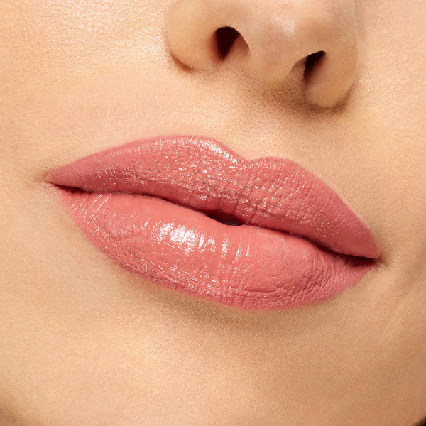 Lips wearing NBD ColourPop Lippie Stix, a warm nude-pink with a creamy, glossy finish, shown in an extreme close-up under studio lighting to display smooth, even coverage and natural shine.