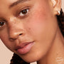 ColourPop Pressed Powder Blush in Papaya dusts a warm peachy flush across a freckled cheek in a close-up, showcasing the pressed powder blush single’s smooth blend and natural finish for everyday wear.