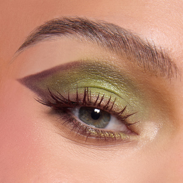 Close-up eye wearing shimmering ogre-green, olive, and chartreuse shadow with a sharp plum cut crease and lengthened lashes, showcasing the Shrek-Spress Yourself ColourPop Lip and Eye Set for bold green glam looks.
