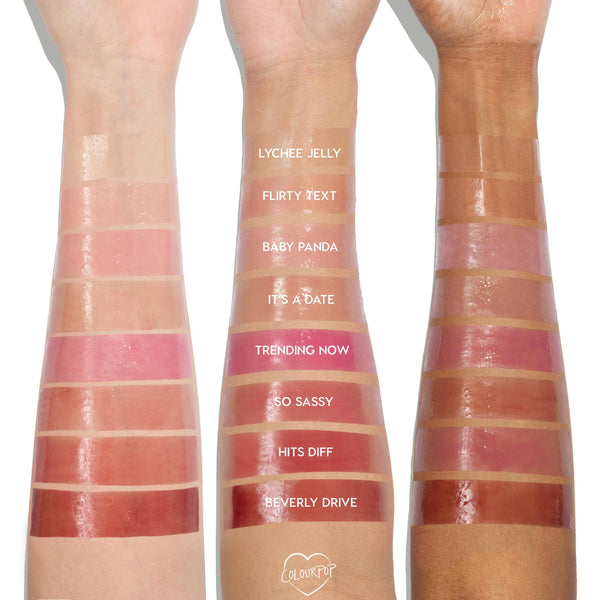ColourPop So Juicy Plumping Glossy Lip Oil shade Trending Now swatched on three arms in light, medium, and deep skin tones, showing a vibrant rosy pink, high-shine finish and plumping gloss texture alongside other labeled shades for comparison.
