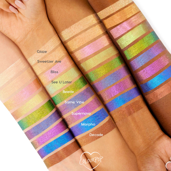 Bliss Chrome Liquid Shadow swatch flashes pink to gold on several skin tones, lined alongside other labeled shades across forearms, showcasing the prismatic, long‑wear finish of ColourPop Chrome Liquid Shadow.