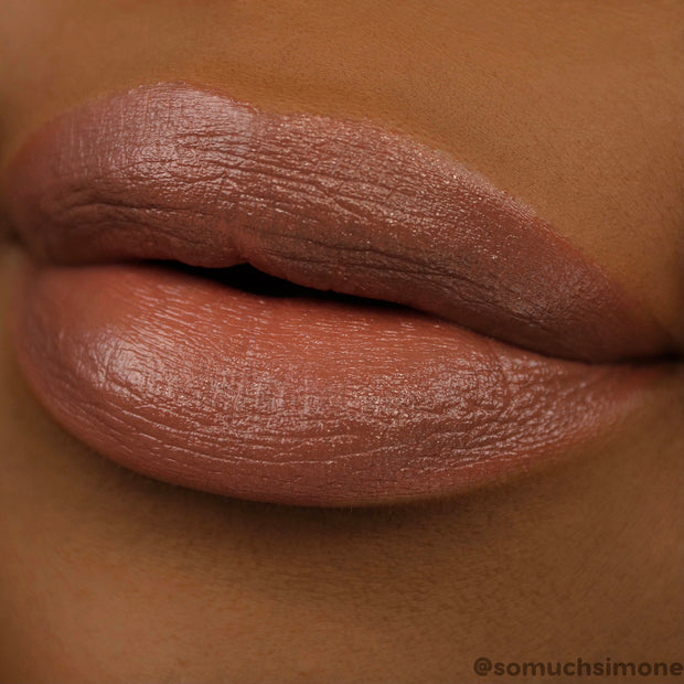 Close-up lips wearing ColourPop Lippie Stix Brat Pack, a creamy satin nude-brown lipstick, showing smooth full-coverage color with a hydrated sheen in a macro swatch on deep skin for shade reference.