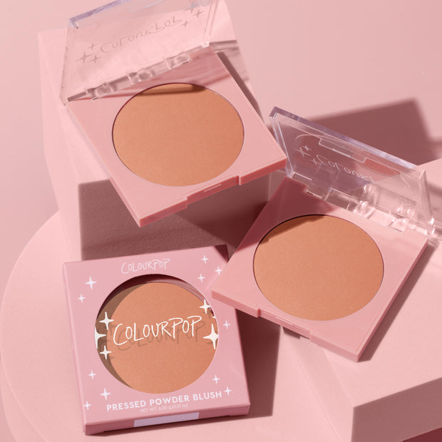 ColourPop Pressed Powder Blush No Rules compact showcasing a warm peach matte pan, two open pink square cases with clear lids and one boxed with star accents, arranged on blush‑pink blocks with soft shadows.