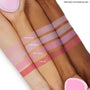 Woo Me pressed powder blush by ColourPop swatched on three arms, showing a rich rosy-pink stripe labeled “WOO ME” under Sweetheart, Cupid’s Bow, and Hot 2 Touch, demonstrating smooth pigment across light, medium, and deep skin tones.